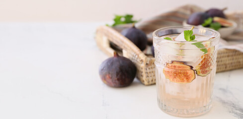 Glass of tasty fig lemonade on light background with space for text