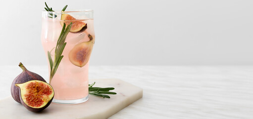 Glass of tasty fig lemonade on light background with space for text