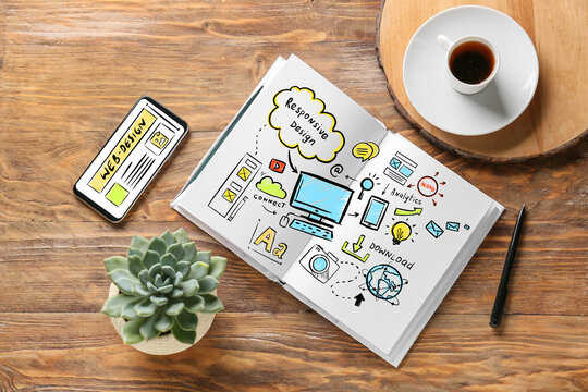 Notebook with sketches of web designer, mobile phone and cup of coffee on wooden background