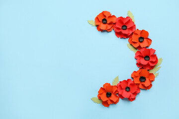 Paper poppy flowers with leaves on blue background