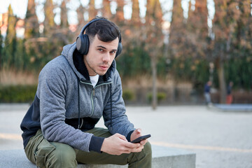 Caucasian young man enjoying music in the park with his headphones on.