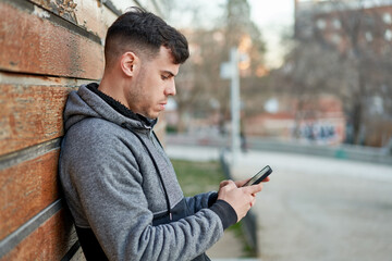 Young caucasian man texting on his phone in the park, staying connected.