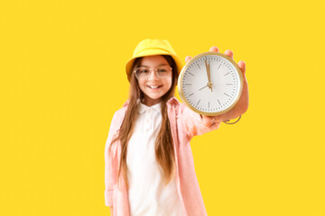 Little girl with alarm clock on yellow background, closeup