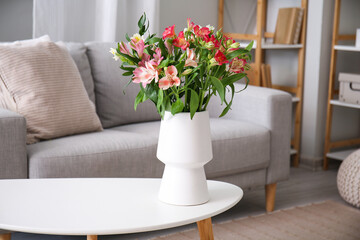 Vase with bouquet of beautiful alstroemeria flowers on table in living room