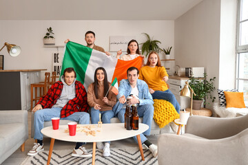 Group of friends with soccer ball and flags of Ireland at home