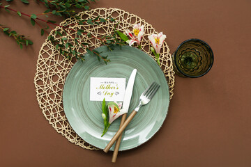 Table setting for Mother's Day celebration with alstroemeria flowers and eucalyptus branches on brown background