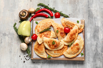 Composition with tasty meat empanadas, vegetables and herbs on grunge background