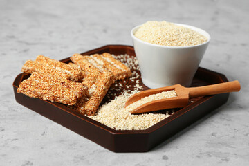 Board with sweet kozinaki and sesame seeds on grunge background