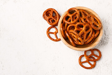 Bowl of tasty salted pretzels on light background