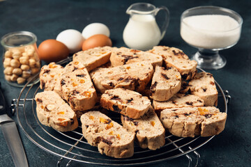 Grid with delicious biscotti cookies, milk, eggs, hazelnuts and sugar on black background