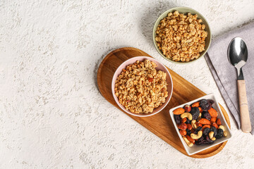 Bowls of tasty granola and nuts on light background