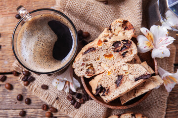 Delicious biscotti cookies, cup of coffee and coffee beans on wooden background