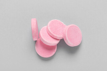 Pink soluble tablets on grey background
