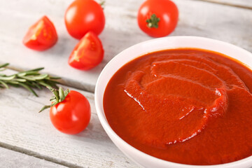 Bowl of tasty tomato paste on wooden background