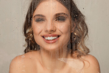 Naklejka premium Beautiful young woman posing through transparent film on grey background