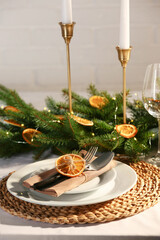Festive place setting with beautiful dishware, fabric napkin and dried orange slice for Christmas dinner on white table