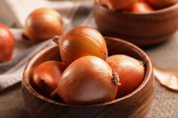 Many ripe onions on wooden table, closeup