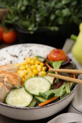 Delicious poke bowl with meat, rice, vegetables and greens on wooden table, closeup