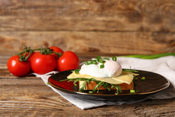 Plate with tasty egg Benedict on wooden background