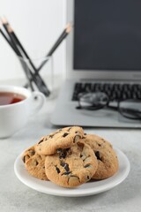 Chocolate chip cookies on light gray table at workplace