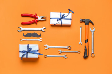 Frame made of paper mustache, gifts and work tools on orange background. Father's Day celebration