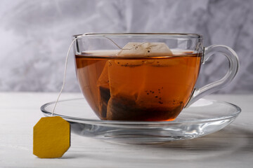 Tea bag in glass cup on white wooden table, closeup