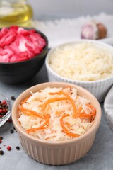 Delicious sauerkraut prepared according to different recipes on light gray table, closeup