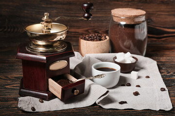 Coffee grinder with powder and cup on wooden table