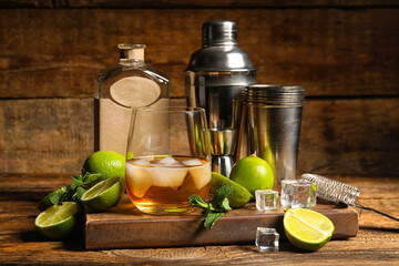 Fototapeta Glass of rum, bottle, shaker, mint and lime on wooden table obraz
