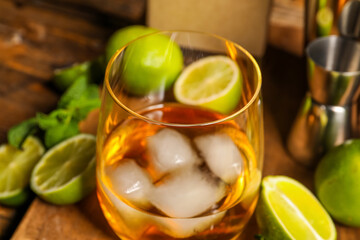 Fototapeta Glass of rum with ice, mint and lime on wooden table, closeup obraz