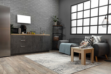 Interior of modern kitchen with black sofa and counters