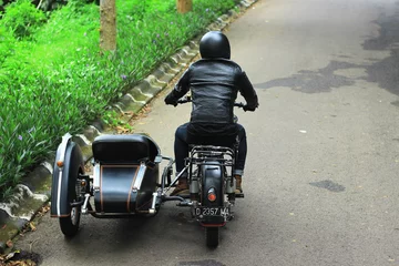 Photo sur Plexiglas Vélo Man riding a black classic European motorcycle on the road in the mountains.