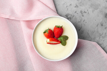 Bowl of tasty semolina porridge with strawberry on grunge background