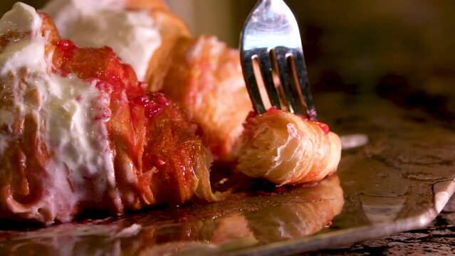 piece of delicious spongy fresh croissant with a fork smear raspberry jam with whipped cream from a plate to saturate the pieces with delicious sweetness Marble plate baking food