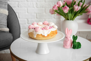 Vase with tulips, Easter cake and toy rabbits on table in living room, closeup