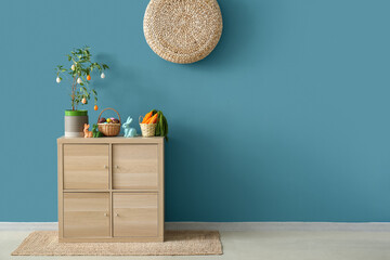 Easter decorations on wooden cabinet near blue wall
