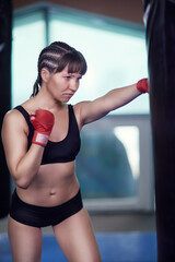 Fototapeta na wymiar Female fighter with a boxing taping bandage on hands boxing on a punching bag .