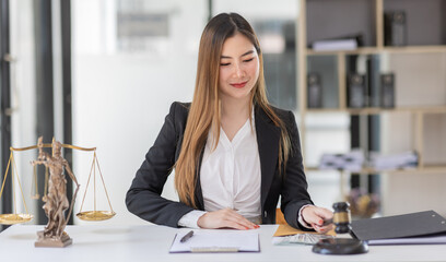 Attractive young lawyer in office Business woman and lawyers discussing contract papers with brass scale on wooden desk in office. Law, legal services, advice, Justice and real estate concept.