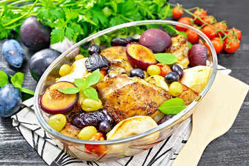 Chicken with fruits and tomatoes in glass pan on napkin