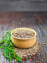 Cumin seeds in bowl with herbs on wooden board