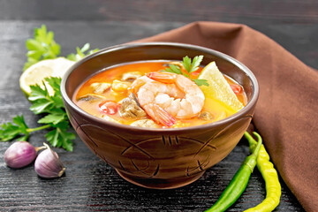 Soup Tom Yum with lemons in bowl on board