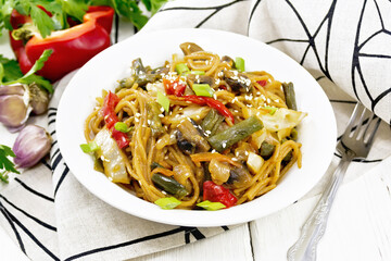 Spaghetti buckwheat with vegetables in plate on light board