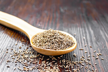 Cumin seeds in spoon on dark board