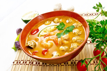 Soup Tom Yum with lime in bowl on light board