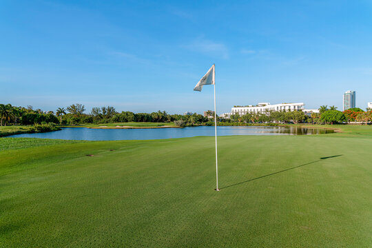MIAMI, FLORIDA - CIRCA JULY, 2022: Flag on golf course of Miami Beach Golf Club. There is a flag at the front near the lake at the back.