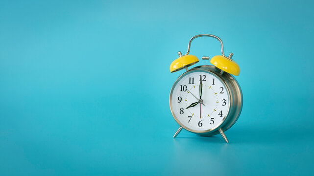 Retro silver alarm clock. 7:00, am, pm. Blue background.