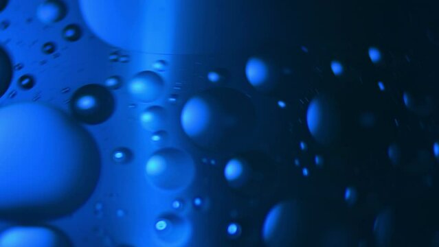 Swirling bubbles of oil in water shot through blue colored jell.