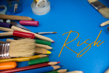 Overhead shot of school supplies with Risk text. Brushes, pencils, artistic tools. Art And Craft Work Tools.