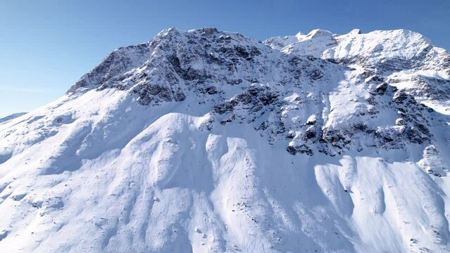 Aerial view of snow covered mountain landscape with forests on a sunny winter day in Alp Grum, Switzerland.