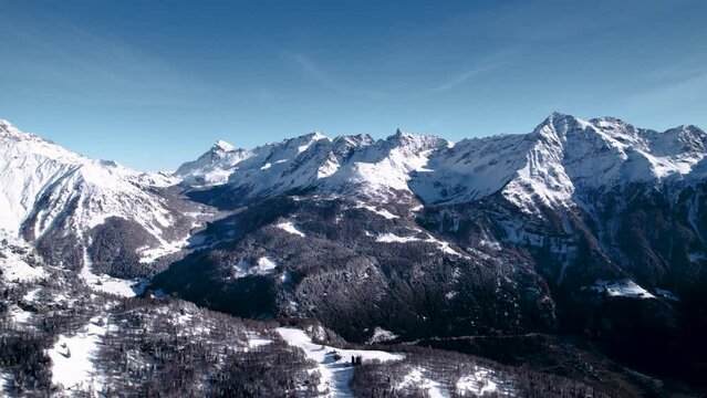 Aerial view of snow covered mountain landscape with forests on a sunny winter day in Alp Grum, Switzerland.
